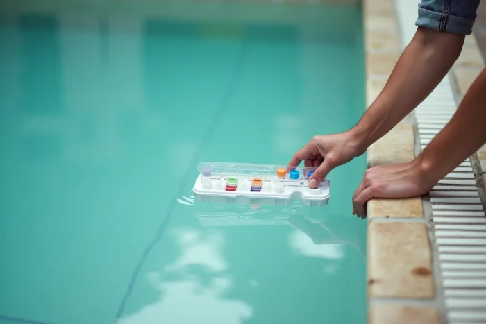 Prélèvement d'un échantillon d'eau de piscine trouble avec kit de test chimique au bord du bassin